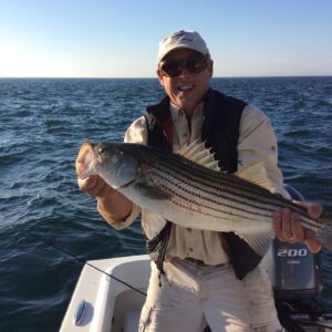 Rollin Schuster of Cross Current Insurance with striped bass catch on Martha's Vineyard