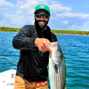Cross Current Insurance's Sales Manager, Dan Phelan, displaying his striper catch while fly fishing.