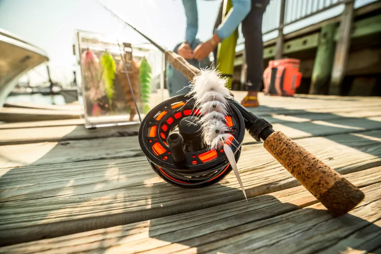 Fly rod and reel on a dock with angler in the background