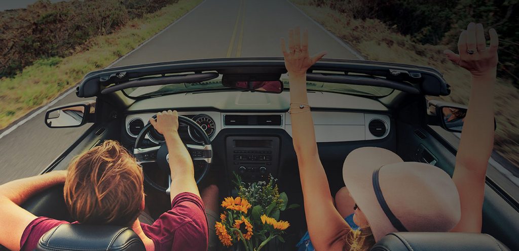 Man and woman driving in a convertible car