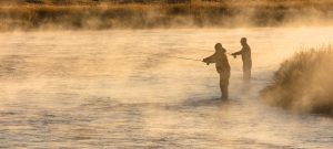 Fly fishing anglers in a misty Montana river.
